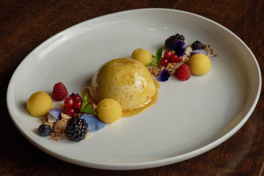 Elegant dessert presentation featuring a dome cake with fresh berries and edible flowers.