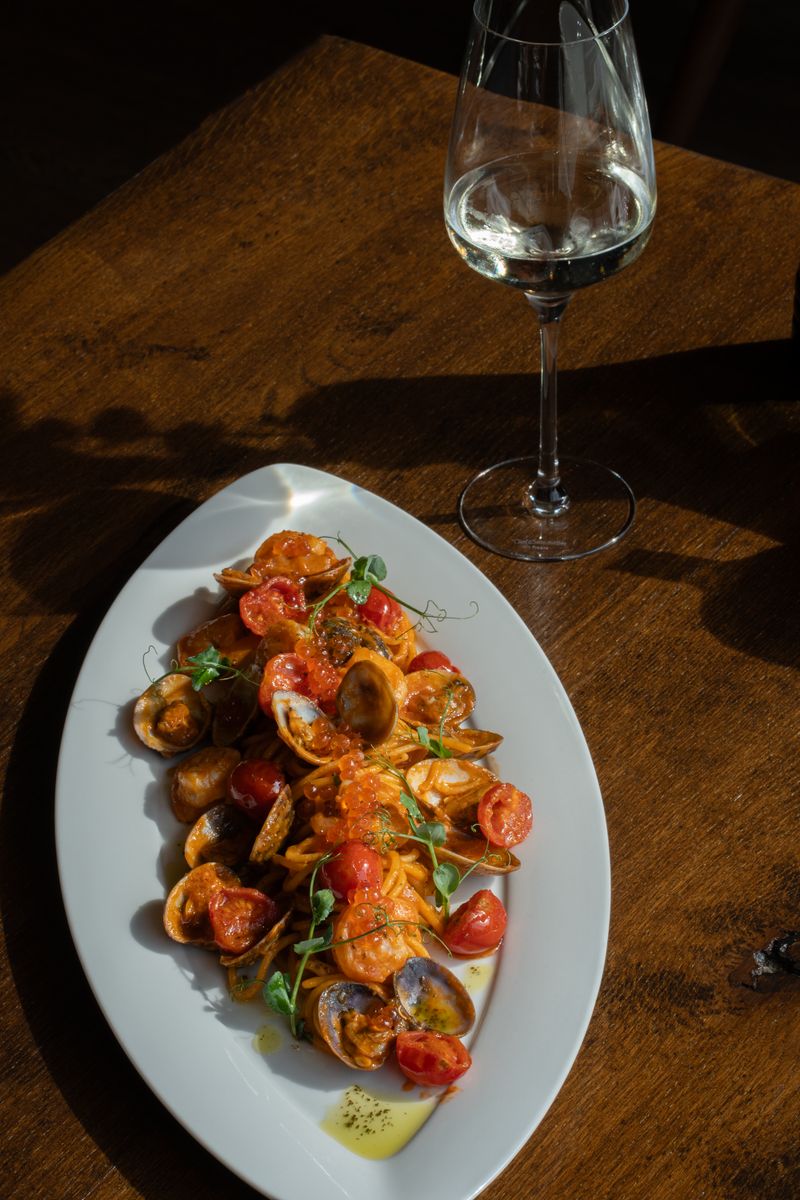 Elegant seafood pasta dish with fresh tomatoes and herbs, paired with a glass of white wine.