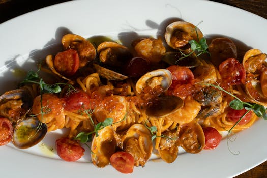 Close-up of a seafood pasta dish garnished with fresh herbs and cherry tomatoes.