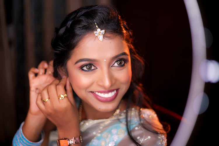 Smiling Woman Staring In Mirror Putting On Earrings 