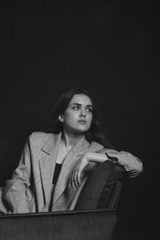 Black and white studio portrait of a woman posing elegantly in a blazer, exuding fashion and elegance.