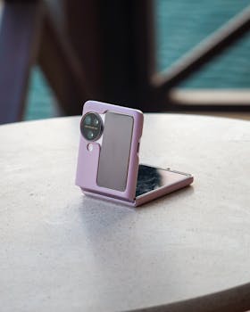 Close-up of a foldable smartphone in a purple case on a table outdoors.