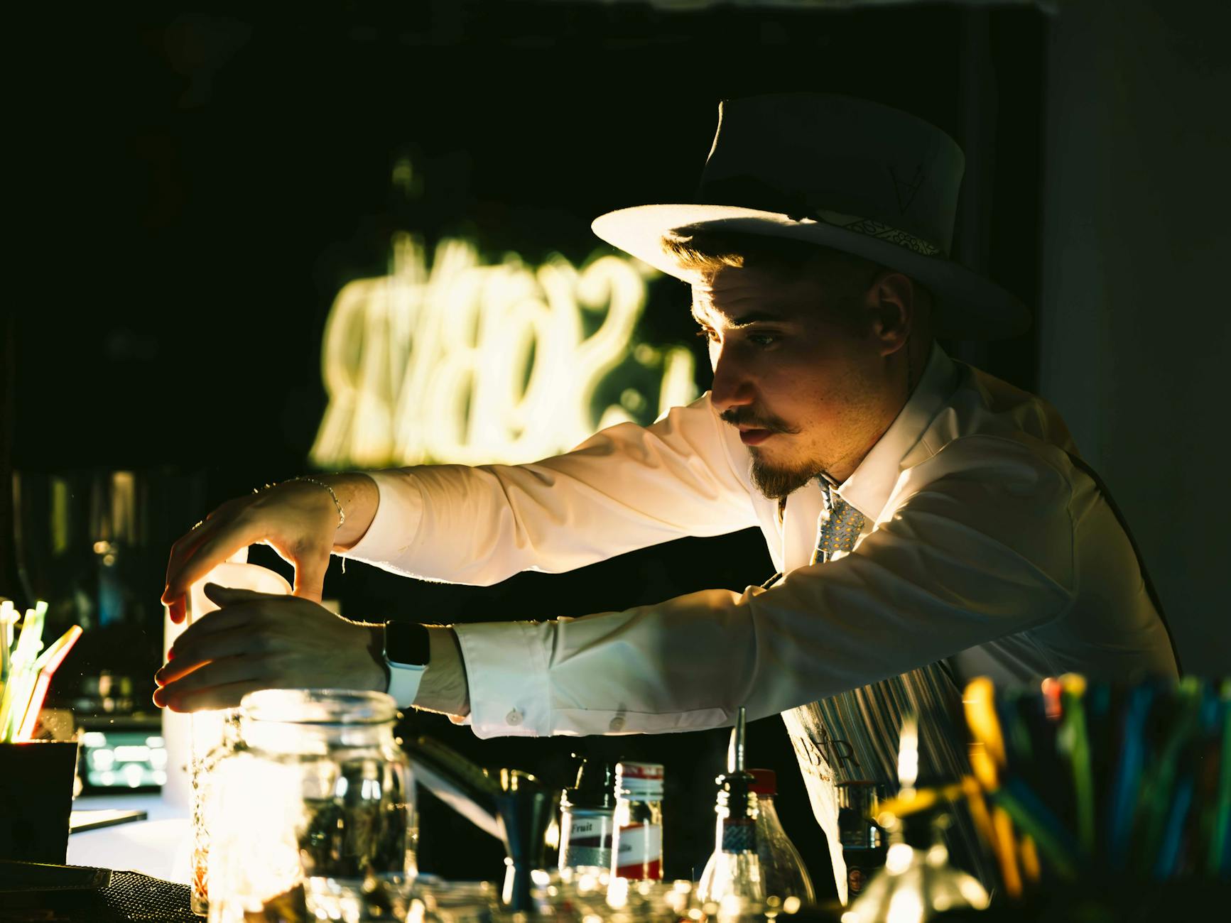 Bartender focused on mixing drinks behind a dimly lit professional bar