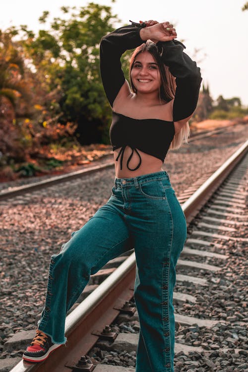 Young Woman in Jeans Posing on Railway Tracks