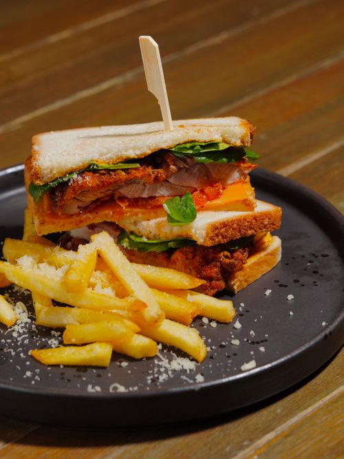 Free A mouthwatering club sandwich served with crispy french fries on a black plate. Stock Photo