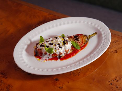 Close-up of a gourmet stuffed eggplant dish with fresh basil garnish.