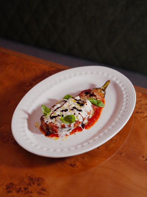 Free Mouthwatering stuffed eggplant with cheese topping and basil garnish on elegant plate. Stock Photo