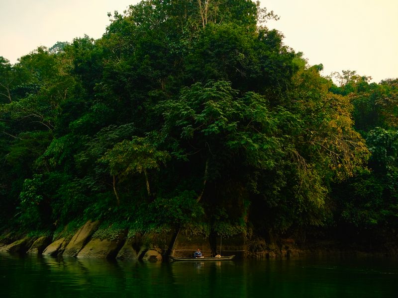Serene river view with dense forest and canoe in Vadattupara