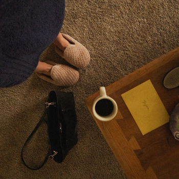 Relaxing morning scene with coffee, bathrobe, and slippers on cozy carpet.
