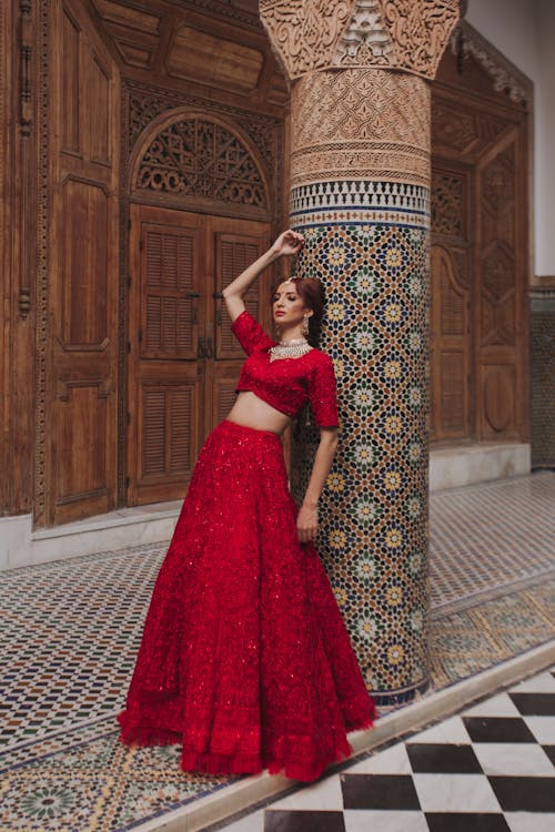 Woman in a Red Sequin Dress Standing Against a Pillar