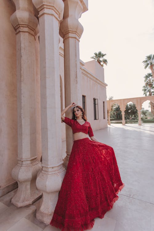 Woman in Red Dress Standing by Building Wall