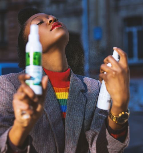 Free Elegant woman enjoying skincare routine with sprays in an urban setting. Stock Photo