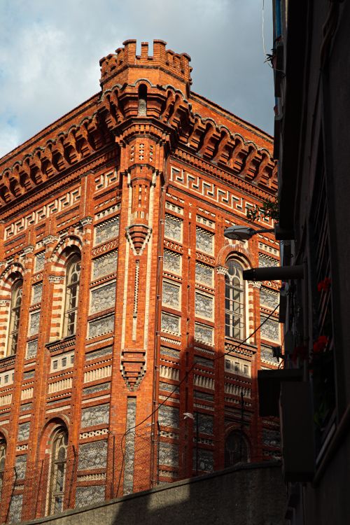 Free A historic red brick building showcasing intricate architectural details under a clear sky. Stock Photo