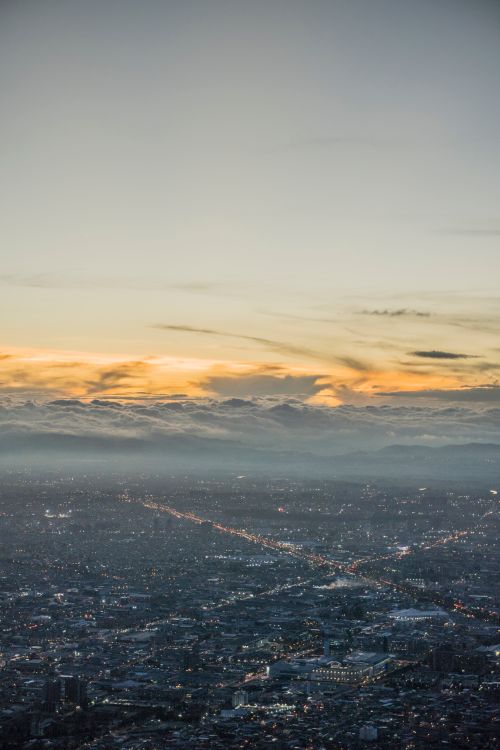 Free Breathtaking aerial view of Bogotá, Colombia, illuminated at sunset with cloud-covered mountains. Stock Photo