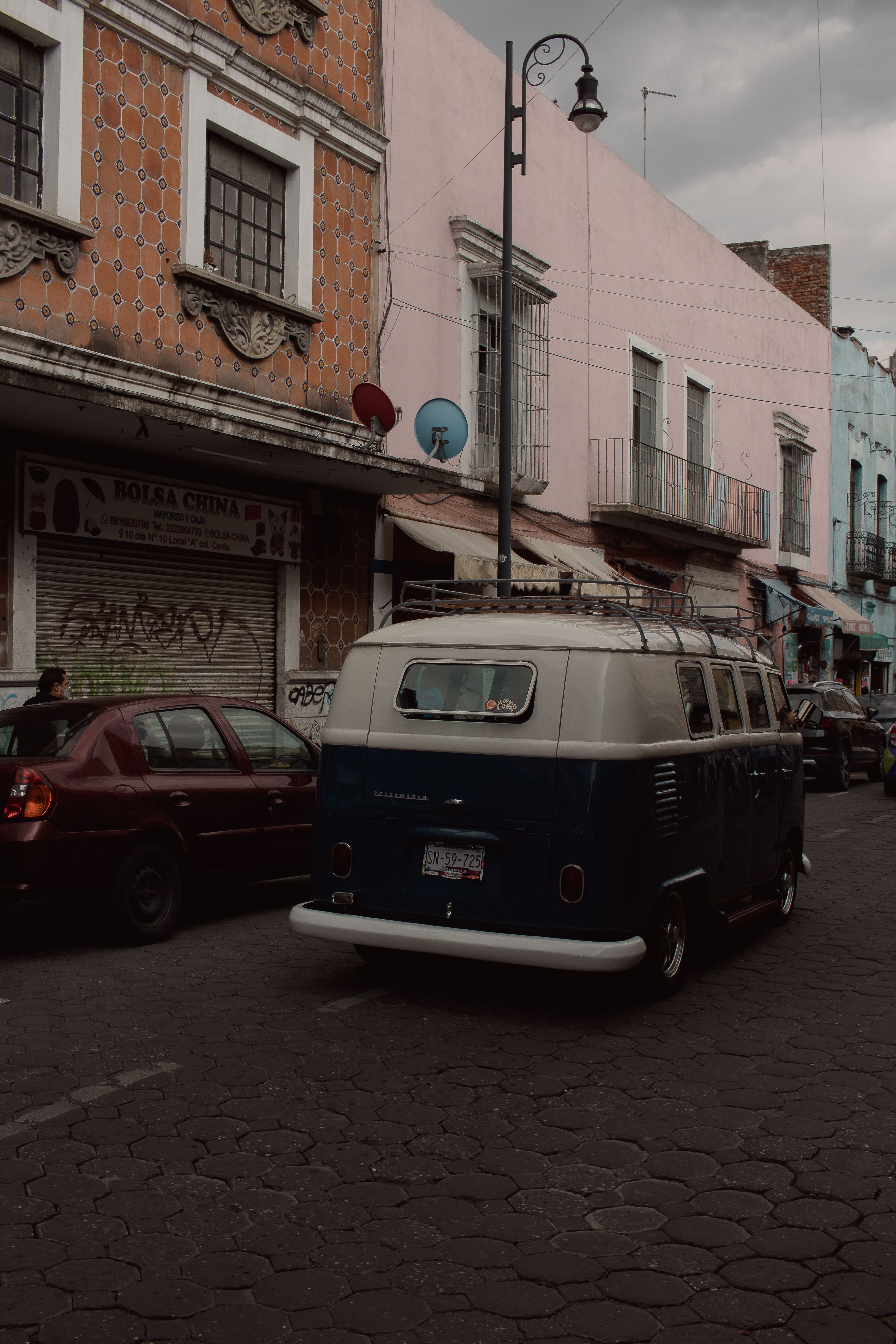 A classic Volkswagen van parked on a historic street in Puebla, Mexico, featuring colorful colonial architecture.