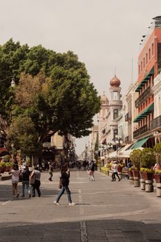 Vibrant street in Puebla, Mexico with people walking and historic buildings in view.