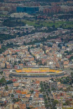 Stunning aerial view of Bogotá, Colombia featuring a prominent stadium and urban architecture.