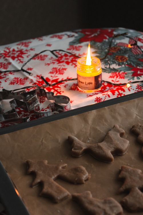 Free Gingerbread cookies on baking sheet with candle, creating a cozy Christmas atmosphere. Stock Photo