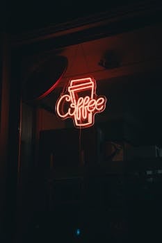 Illuminated neon sign reading 'Coffee' in a dimly lit café window at night.