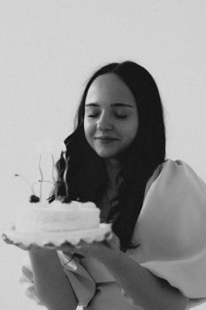 Black and white photo of a young woman joyfully holding a birthday cake.