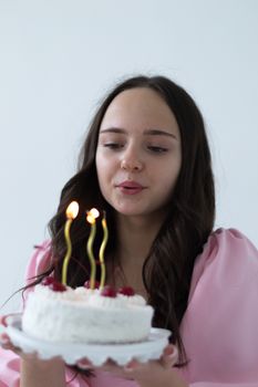 A young woman holds a small birthday cake with lit candles, ready to celebrate.