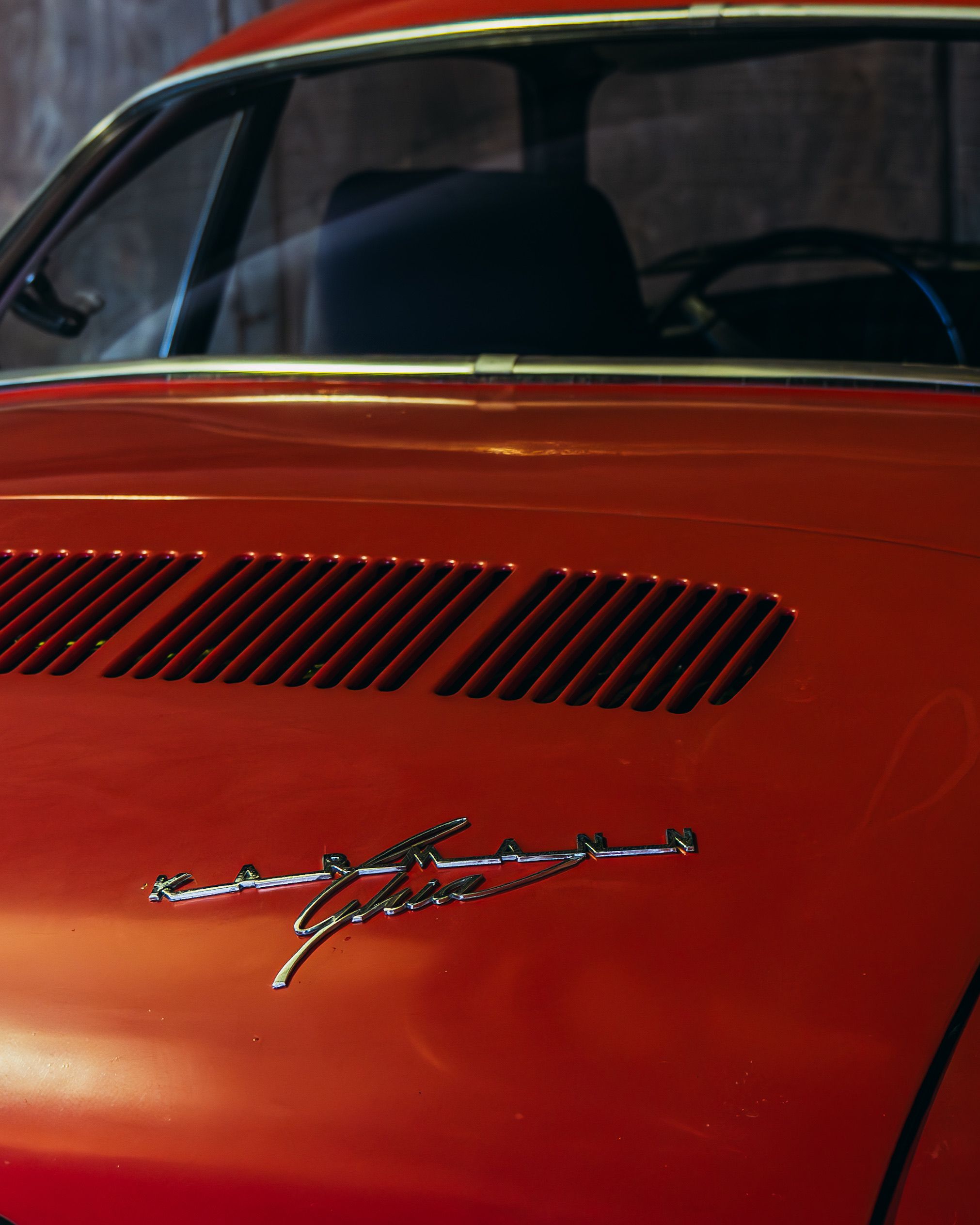 Close-up of a vintage red Volkswagen Karmann Ghia, showcasing retro design elements.