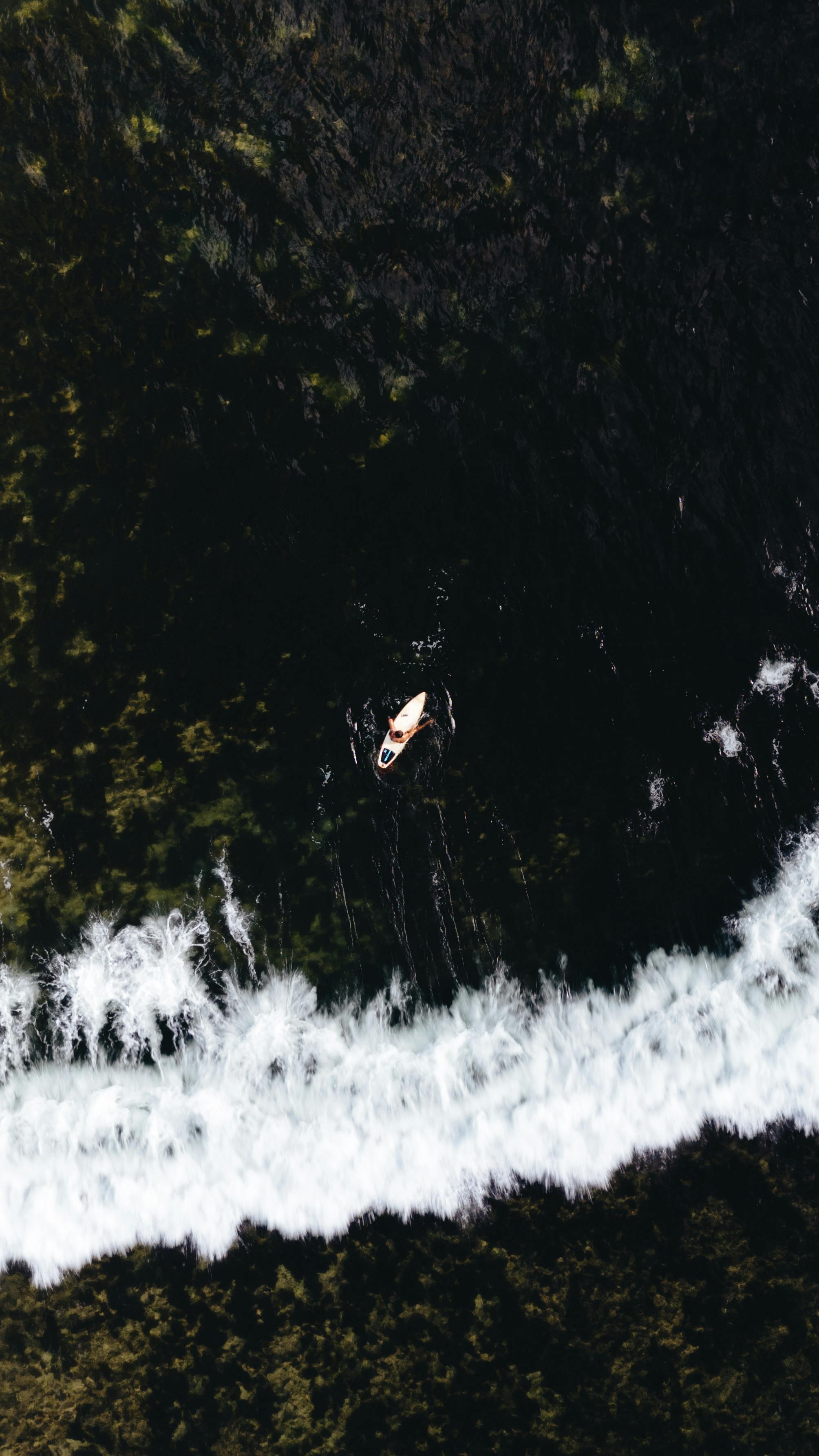 Drone shot of a canoe navigating the dark seas near the shore in General Luna, Philippines.