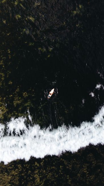Drone shot of a canoe navigating the dark seas near the shore in General Luna, Philippines.