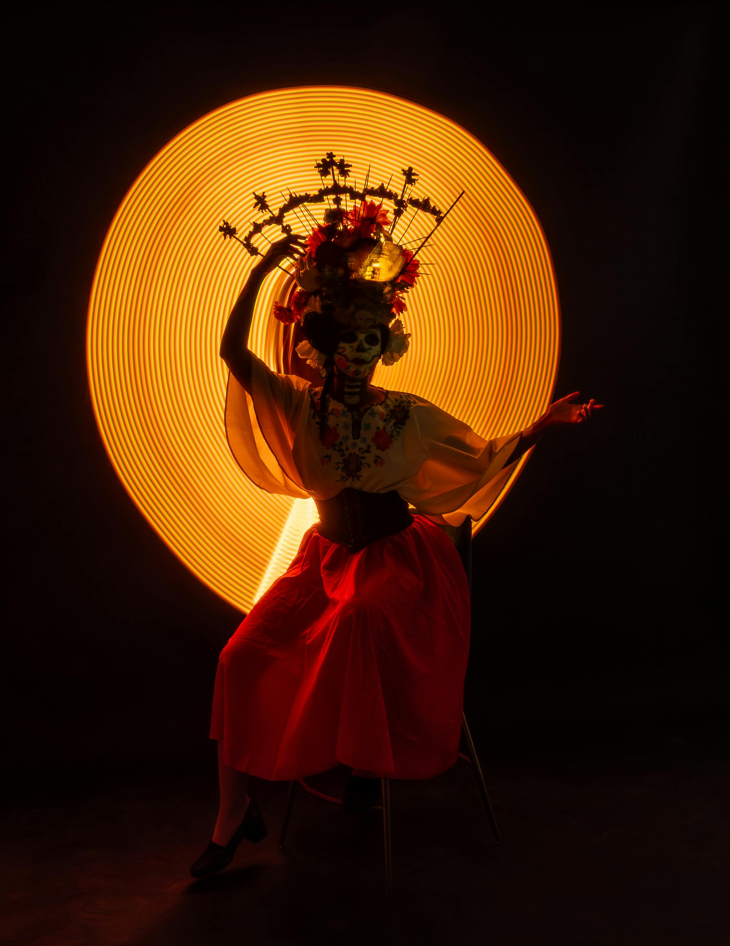 Striking image of a Catrina dancer amidst a vibrant light backdrop in Mexico City.
