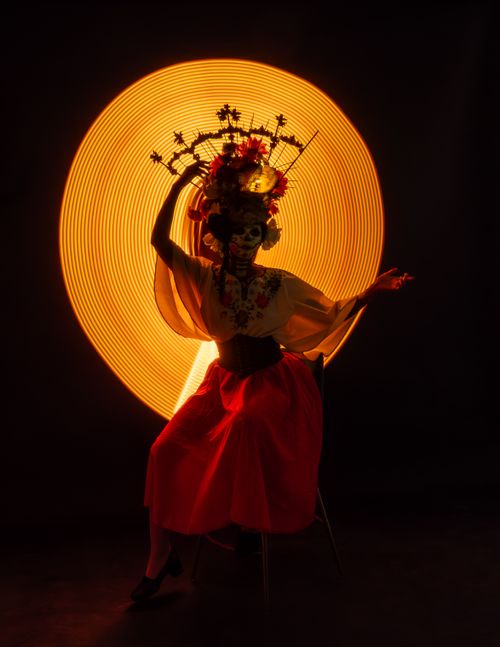 Free Striking image of a Catrina dancer amidst a vibrant light backdrop in Mexico City. Stock Photo