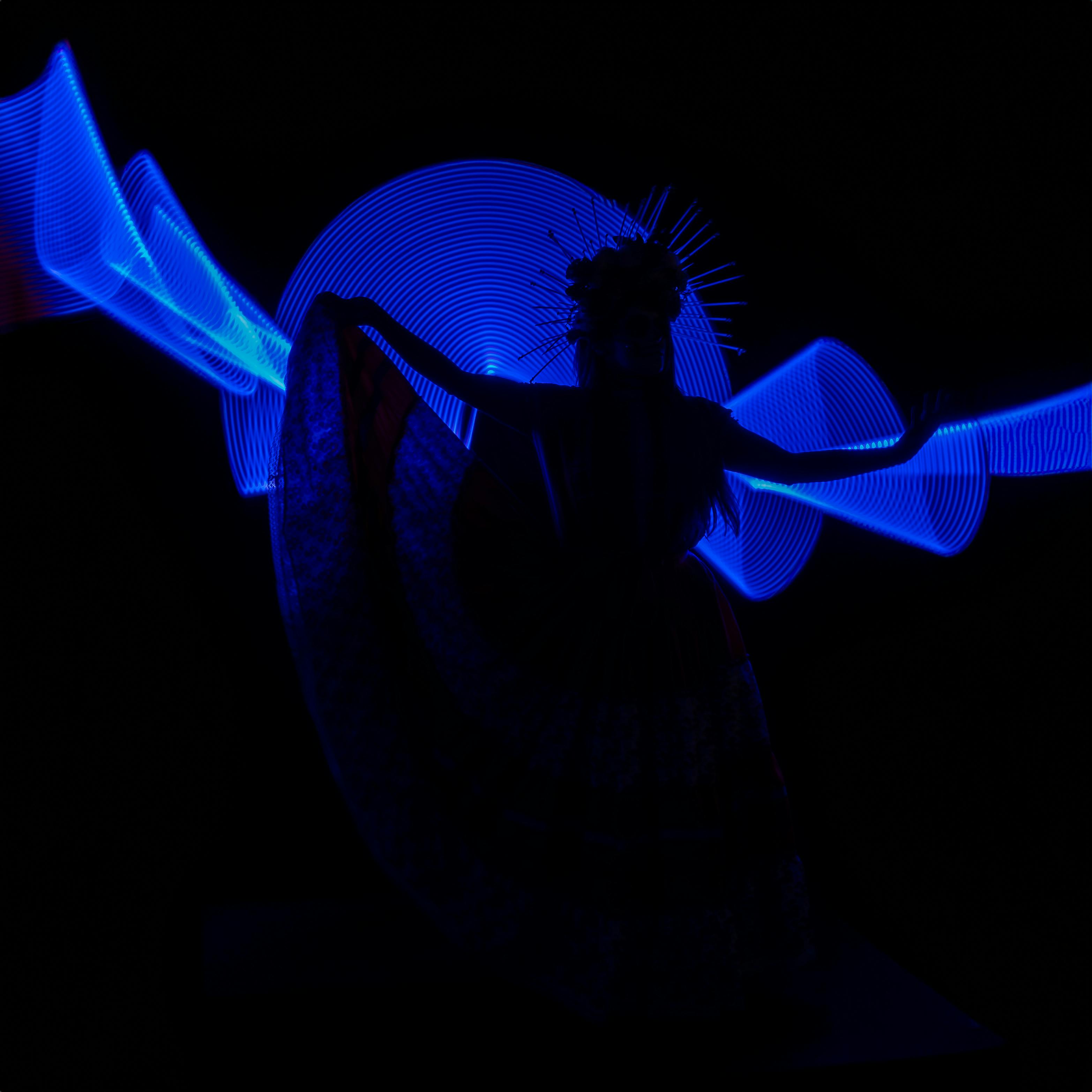 Catrina silhouette with vibrant blue light painting in a cultural dance aesthetic.