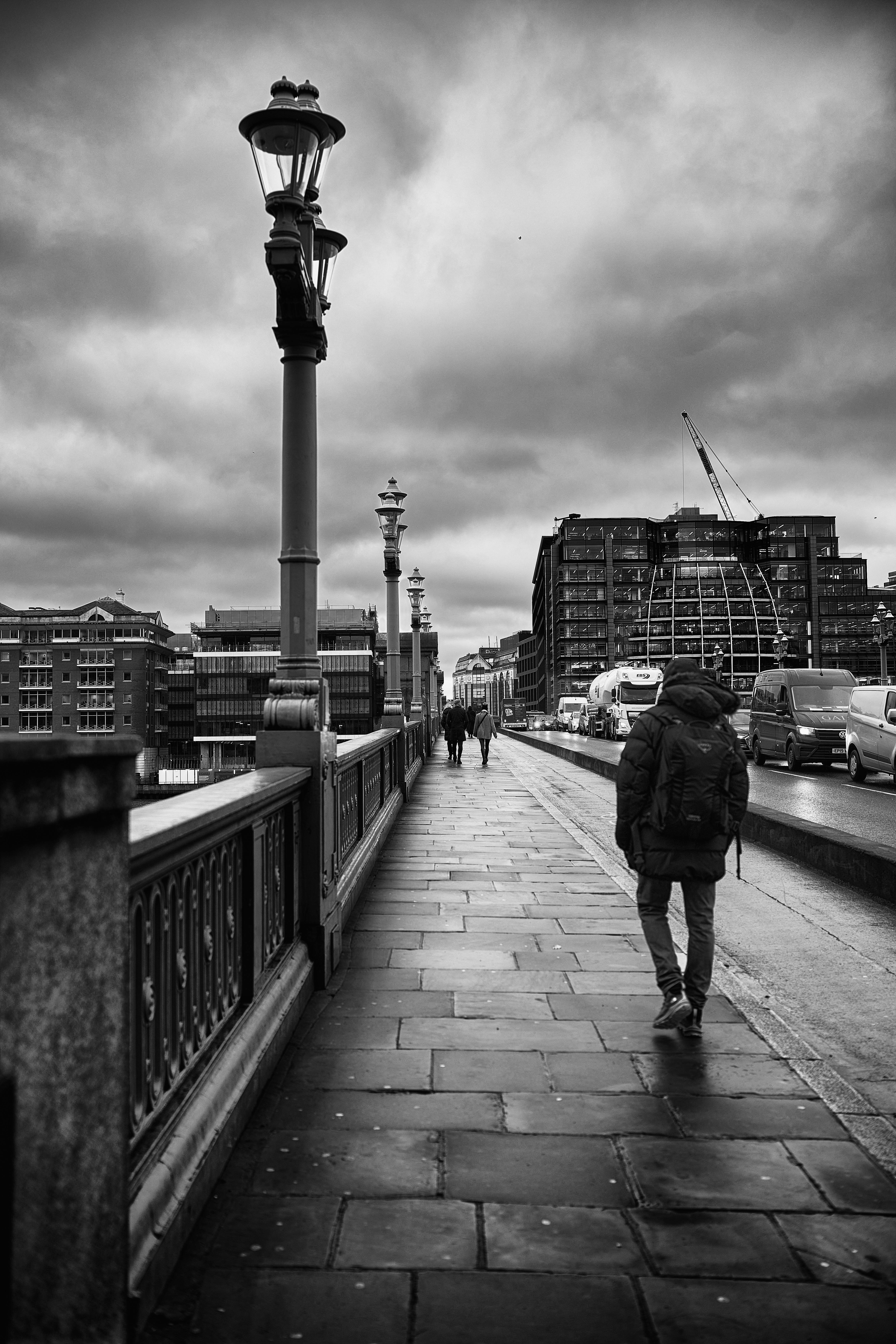 Man with Backpack Walking on Bridge in Black and White Free