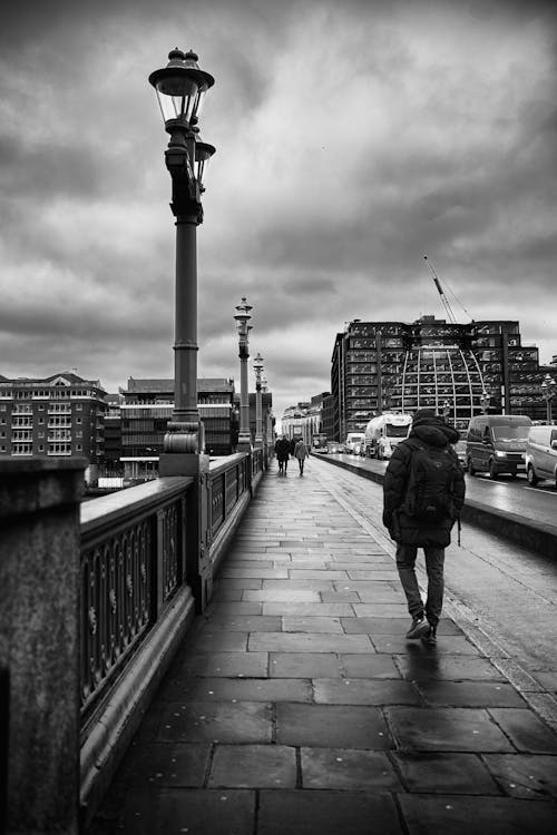 Man with Backpack Walking on Bridge in Black and White