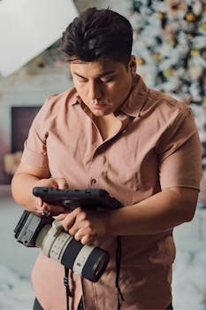 A photographer analyzes pictures on a tablet in a studio setting. Professional camera setup visible.