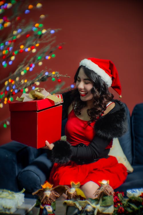 Smiling Woman in Santa Hat Sitting with Christmas Gift
