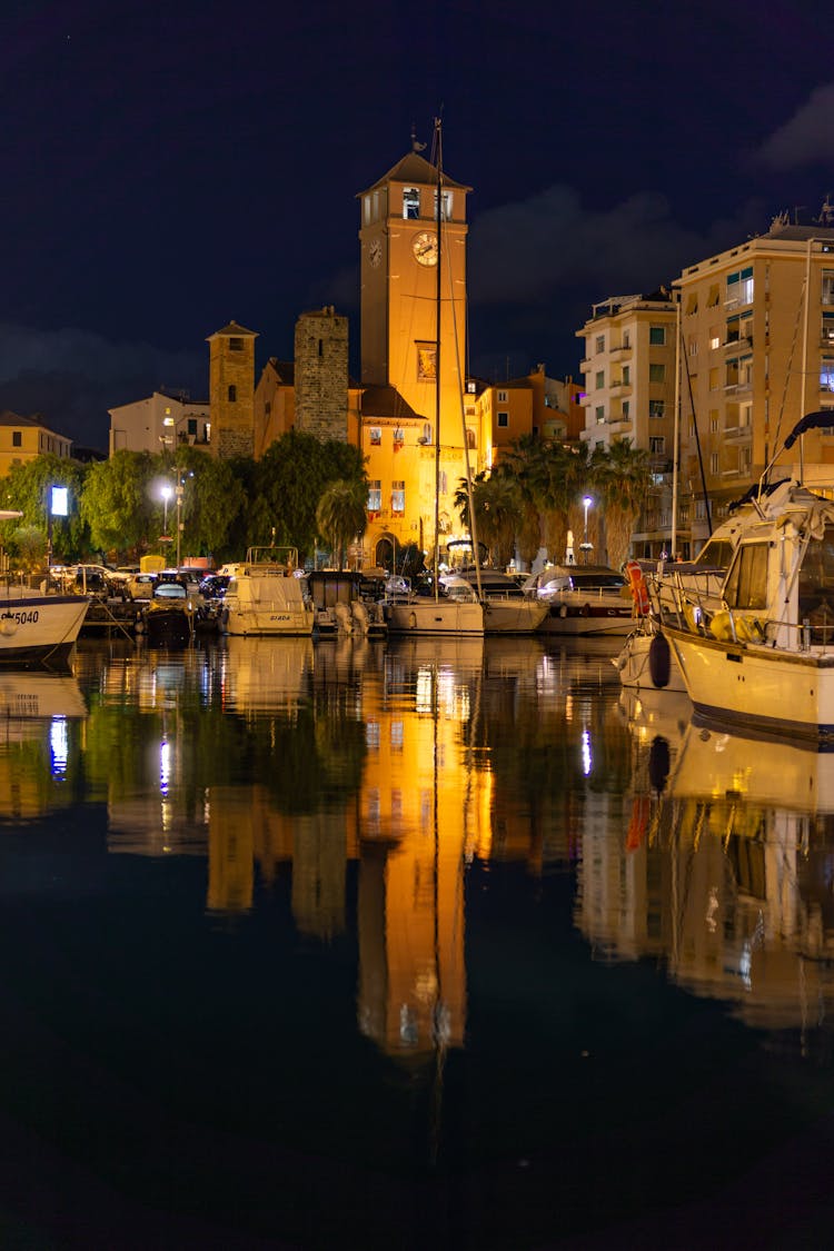 Motorboats Moored Near Tower In Town At Night