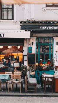 A lively streetview of an urban cafe with outdoor seating and vibrant decor.