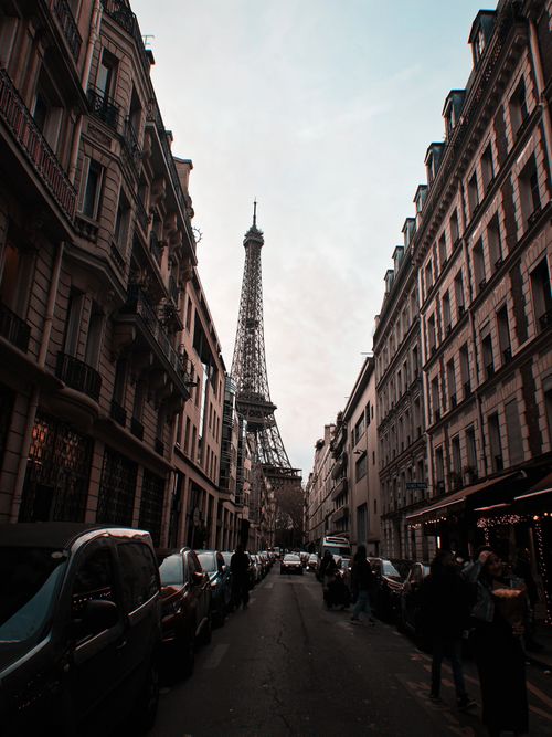 Free A bustling Paris street leading to the iconic Eiffel Tower at dusk. Stock Photo