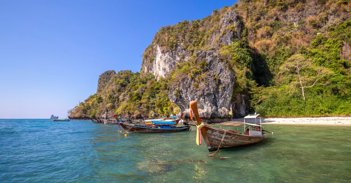 traditional wooden longtail boat on turquoise water near tropical island