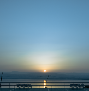 A tranquil sunrise with a minimalistic view over a calm lake and distant mountains.