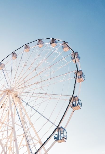 A high-angle shot of a Ferris wheel with clear blue sky, perfect for theme park themes and backgrounds.