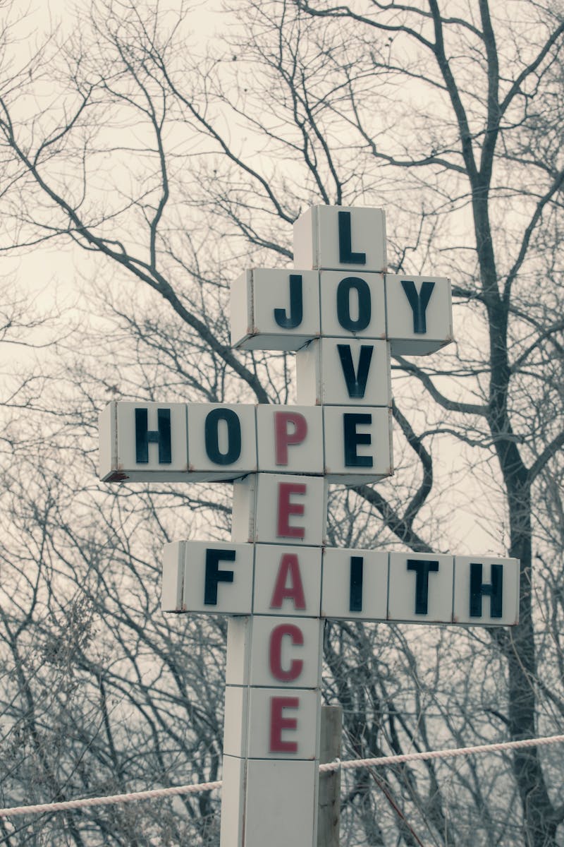 Sign with motivational words during winter, surrounded by barren trees.