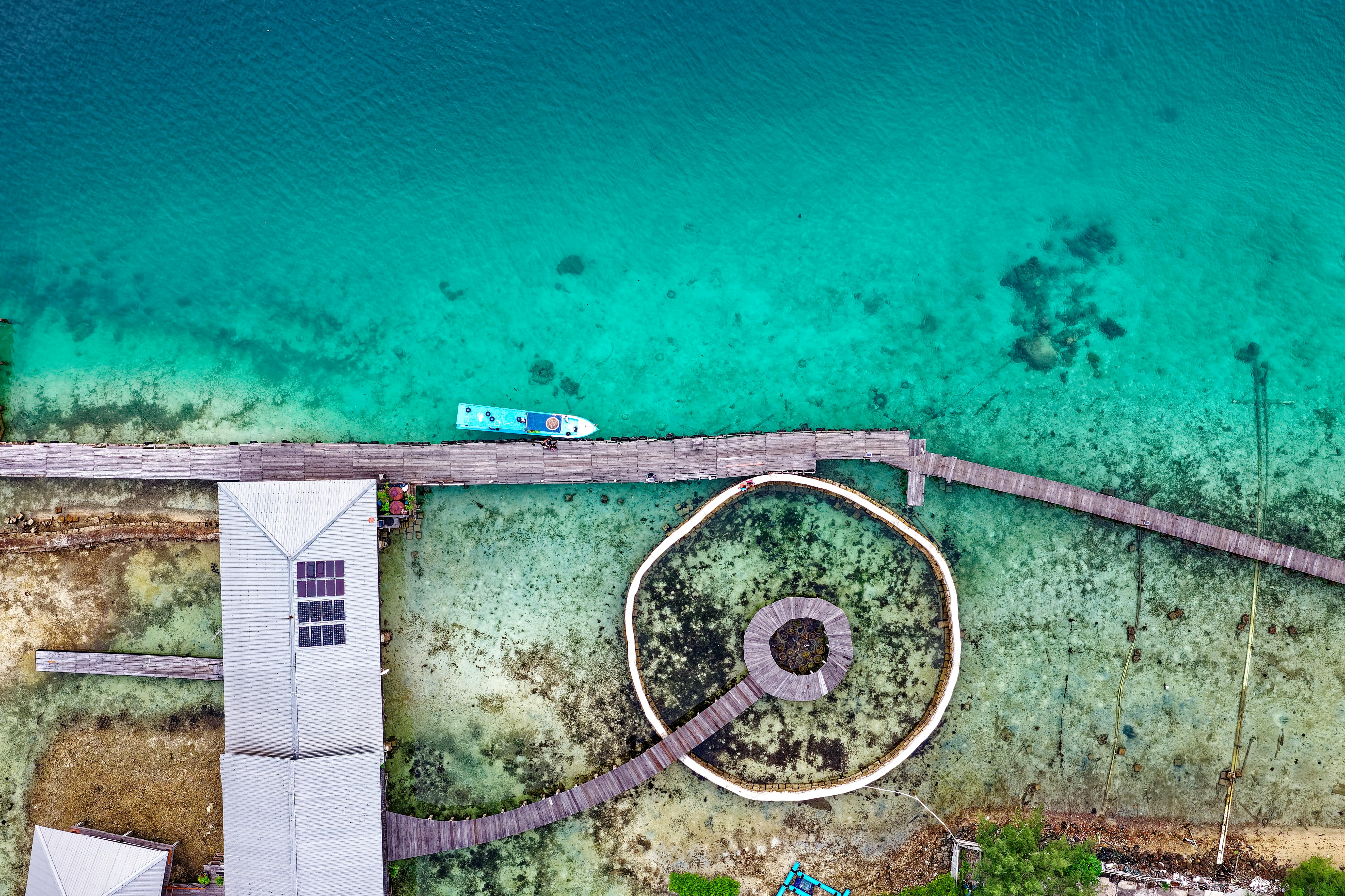 航拍镜头令人惊叹地捕捉到了印度尼西亚碧绿水面上一个带有几何图案的码头