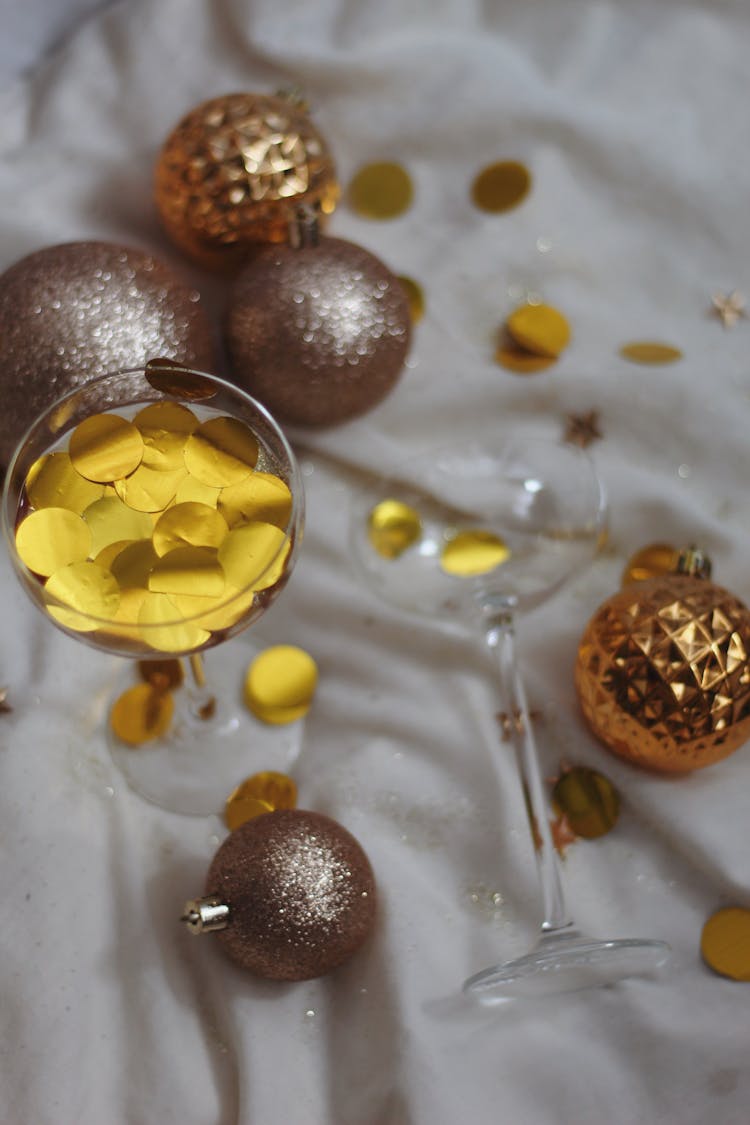 Cocktail Glasses With New Years Eve Confetti Among Christmas Ornaments