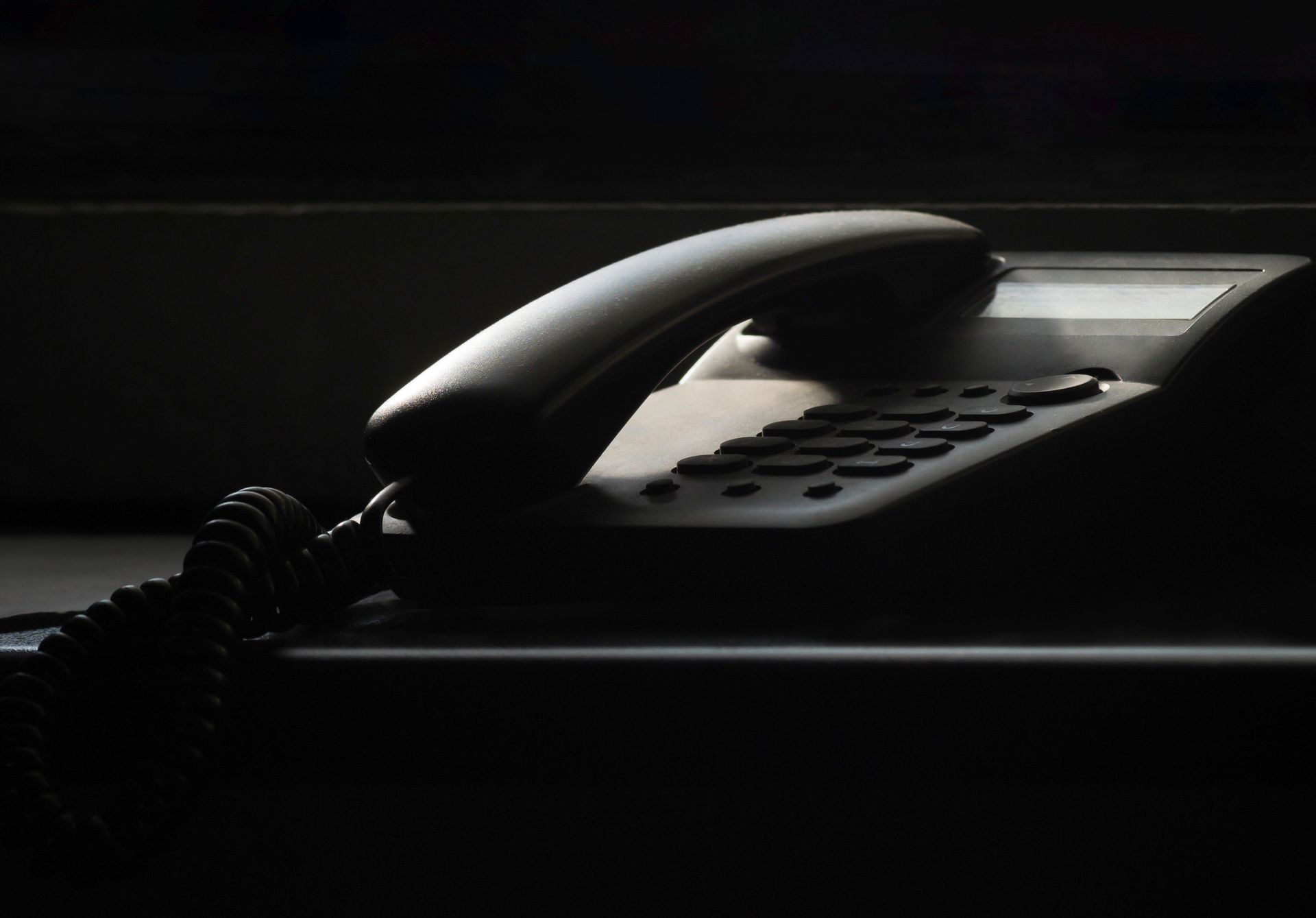 A close-up of a vintage landline phone in dramatic shadow lighting, evoking nostalgia.