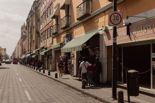 Free Sunlit urban street with historic buildings and pedestrians in Puebla, Mexico. Stock Photo