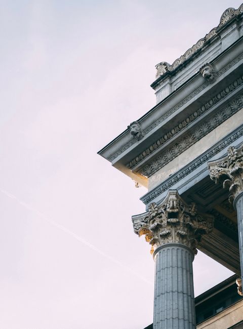 Close-up of Corinthian columns on a neoclassical facade under clear sky with intricate details.