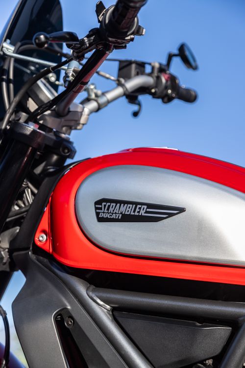 Free A vibrant close-up of a Ducati Scrambler motorbike fuel tank against a clear sky. Stock Photo