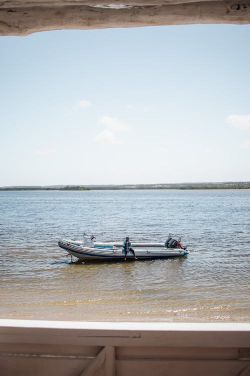 Person Sitting on Motorboat on Sea Shore