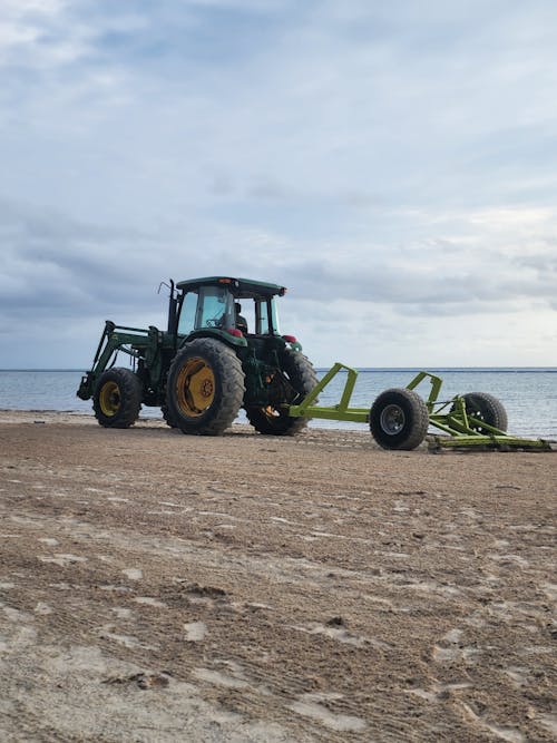 Tractor Pulling Harrow on Sandy Field